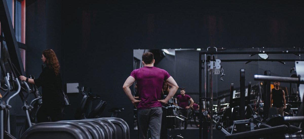 Man in a gym with fitness equipment, highlighting a healthy lifestyle.
